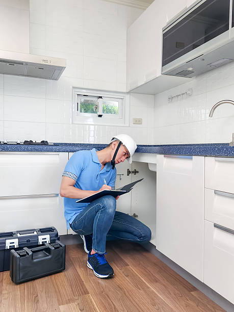 asian male home inspector is checking water leakage situation at kitchen sink